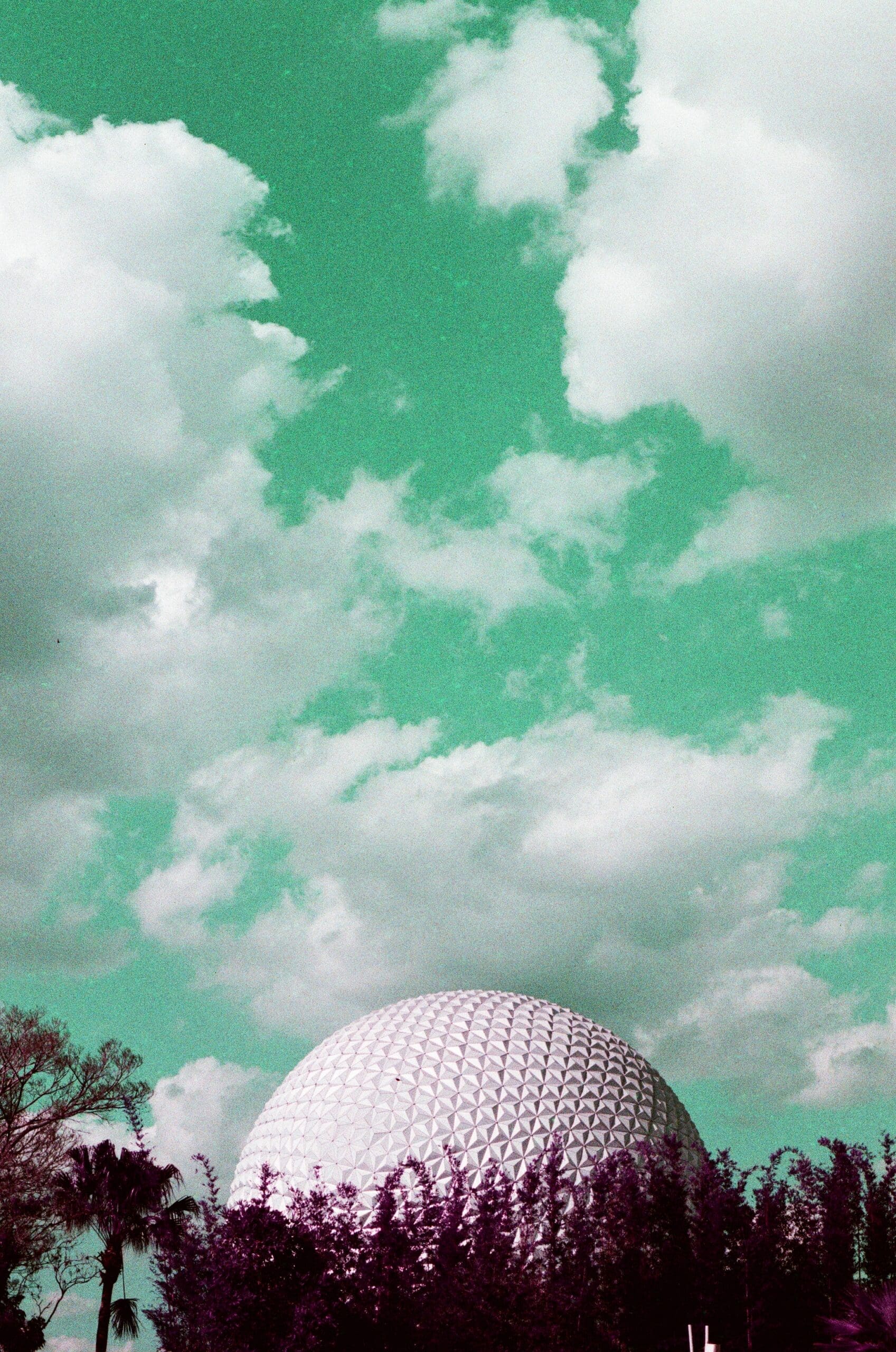 Spaceship Earth geodesic dome against teal sky with purple trees, shot on LomoChrome Purple film
