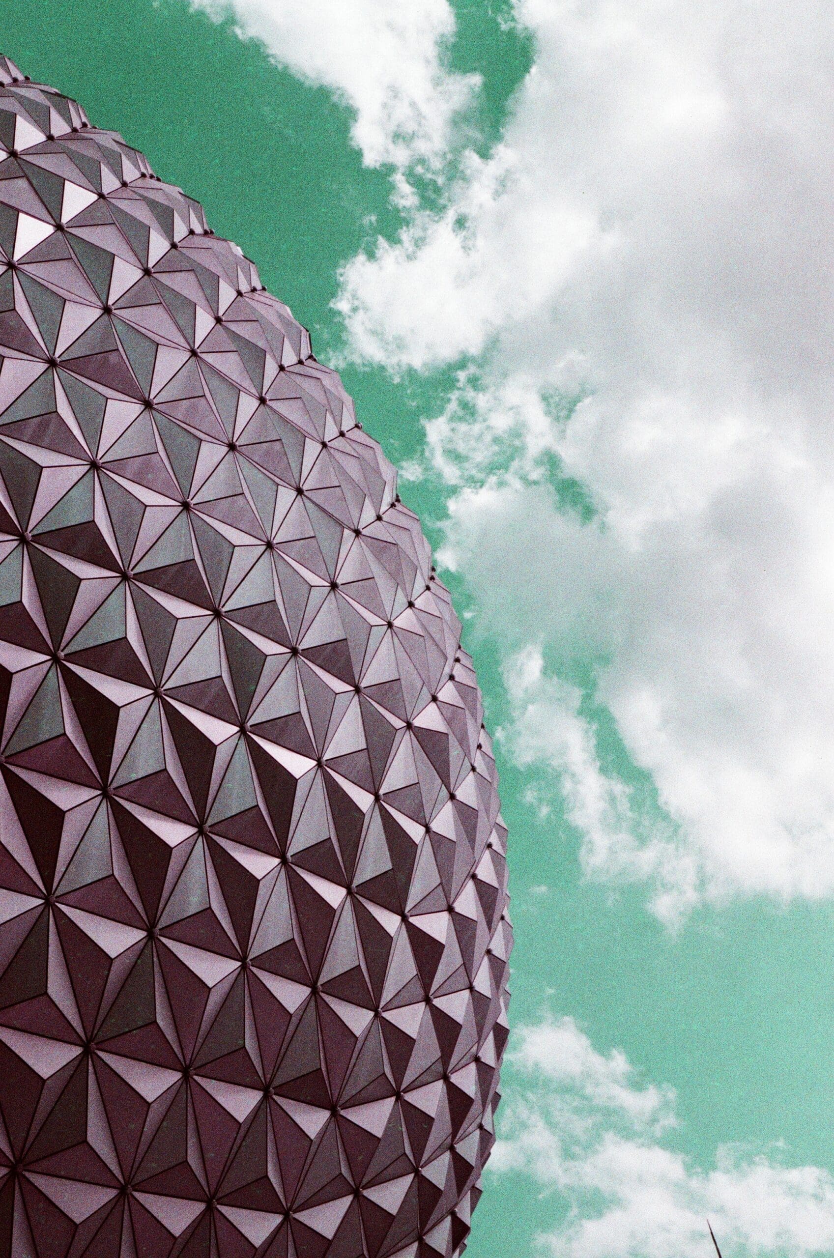 Close-up of Spaceship Earth geometric panels against teal shifted sky, Canon AE-1 Program LomoChrome Purple